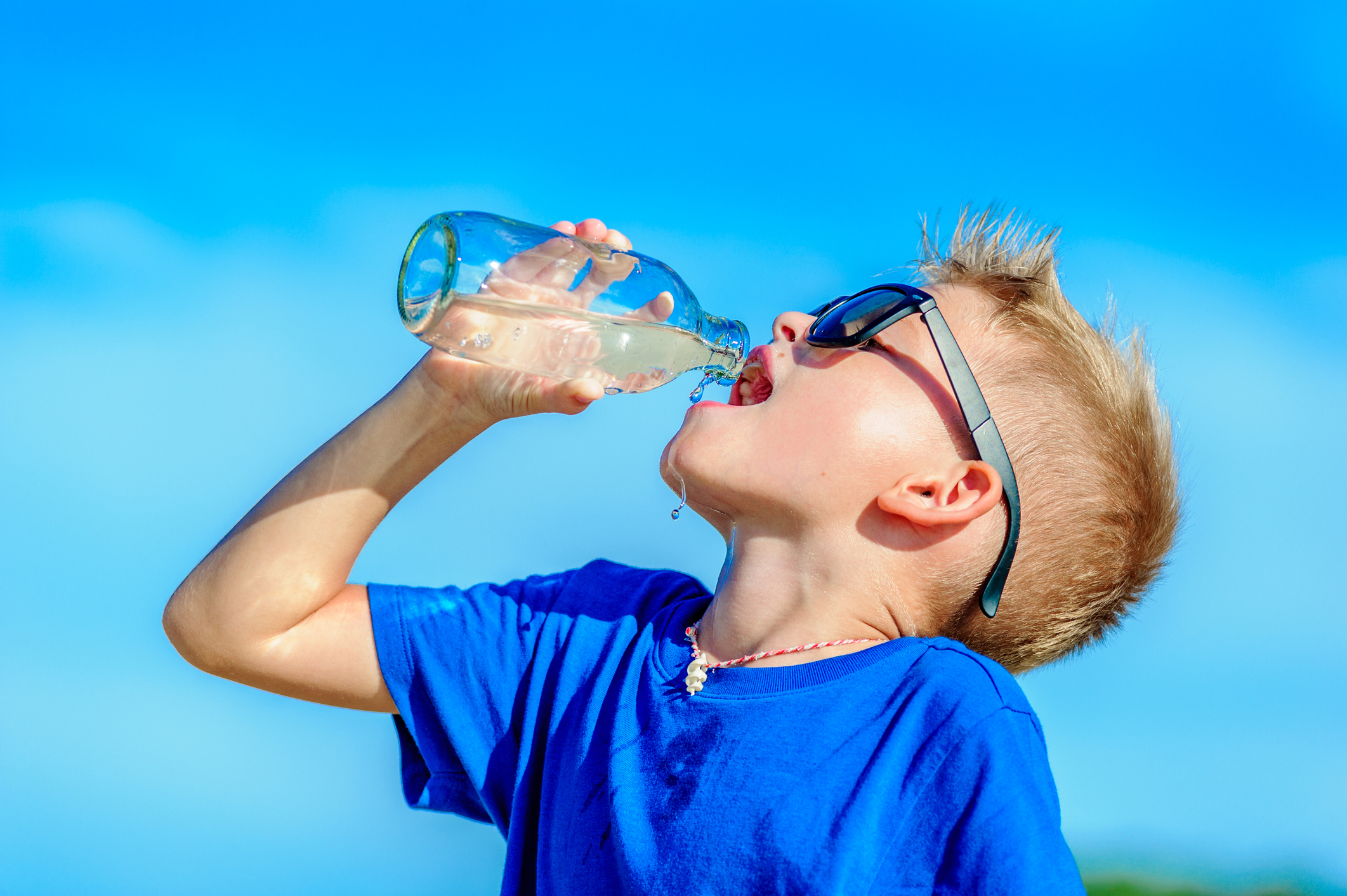 portrait-of-a-thirsty-handsome-boy-in-sunglasses-drinking-water-on-the